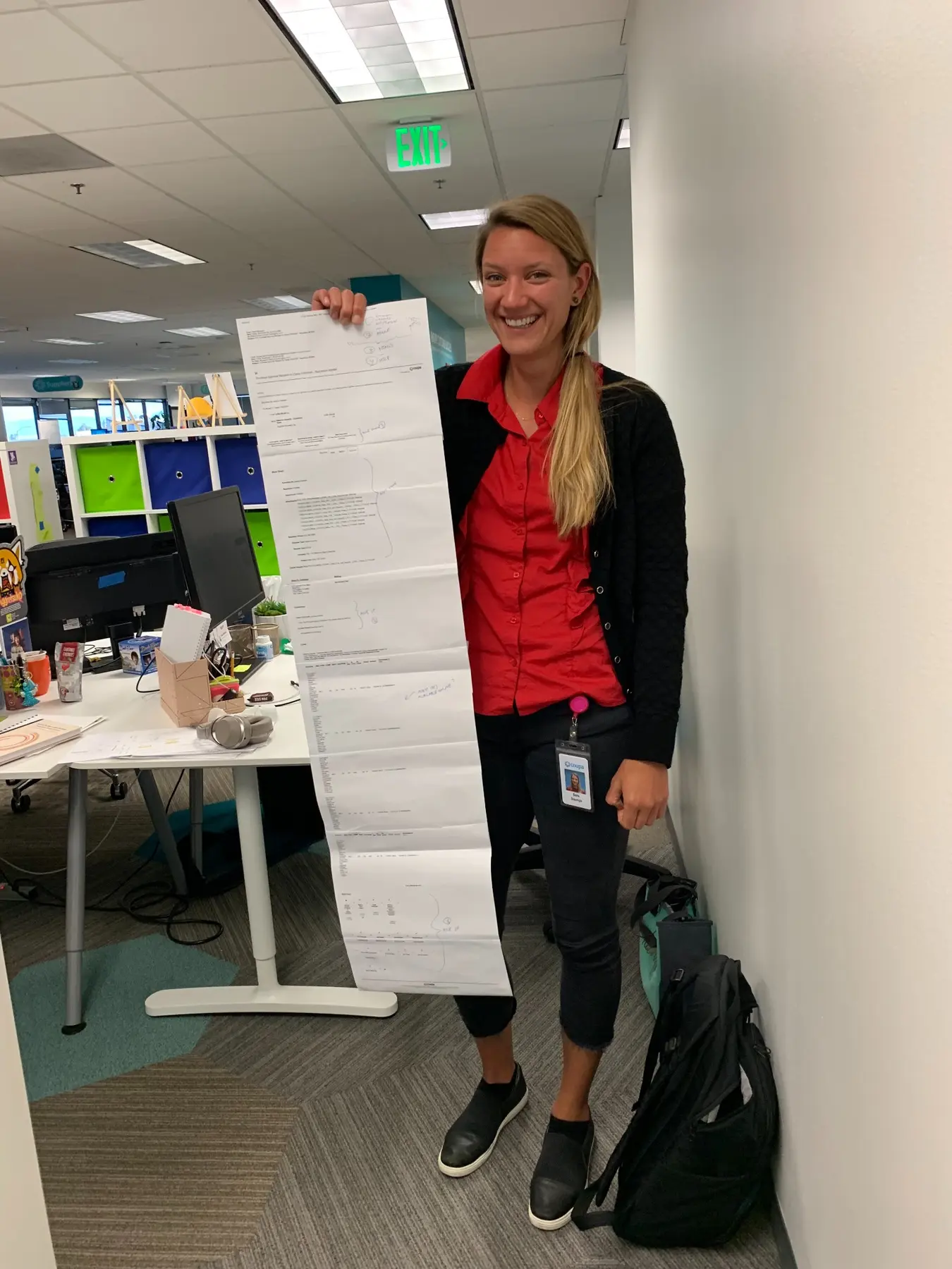 Sara smiling while holding a long printed workflow